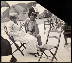 Man and woman seated outside on folding chairs with woman holding a parasol, Narragansett, Rhode Island, 1891
